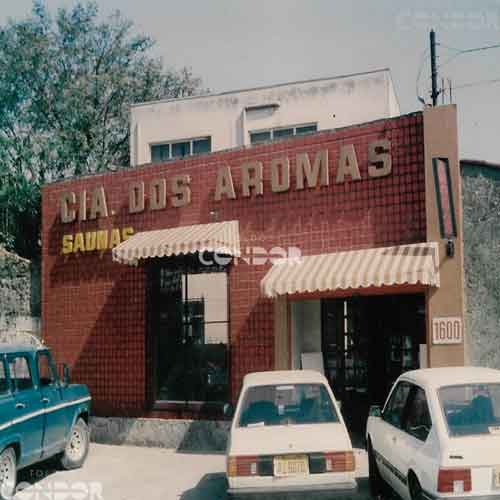 Toldos listrados na faixada de uma loja com carros estacionados.