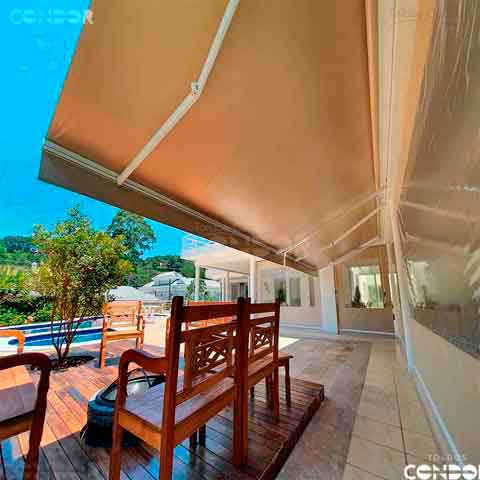 toldo articulado basic protegendo um deck de madeira contra o sol