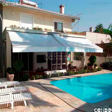 toldo articulado basic com lona branca de frente com uma grande piscina