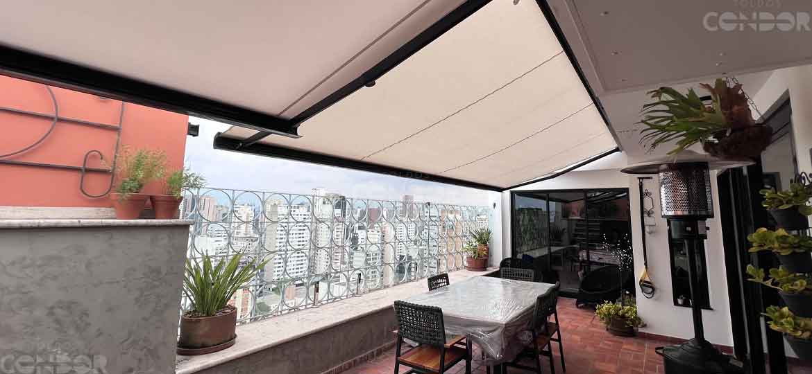 toldos abertos em uma cobertura protegendo a mesa de uma area gourmet