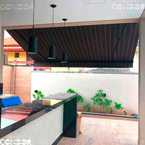 toldo articulado premium com lona listrada sendo visto da parte de dentro de uma area gourmet