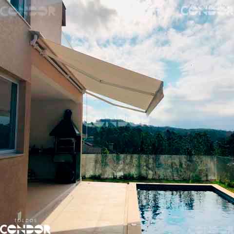 toldo articulado premium em uma area gourme com piscina e vista para uma grande floresta