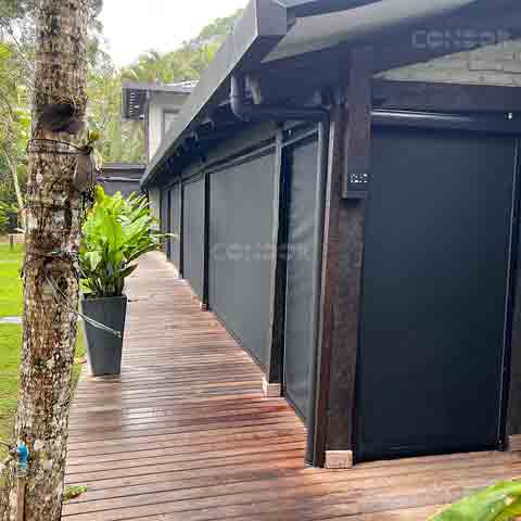 Toldos verticais Premium Blocker instalados em uma casa com deck de madeira.
