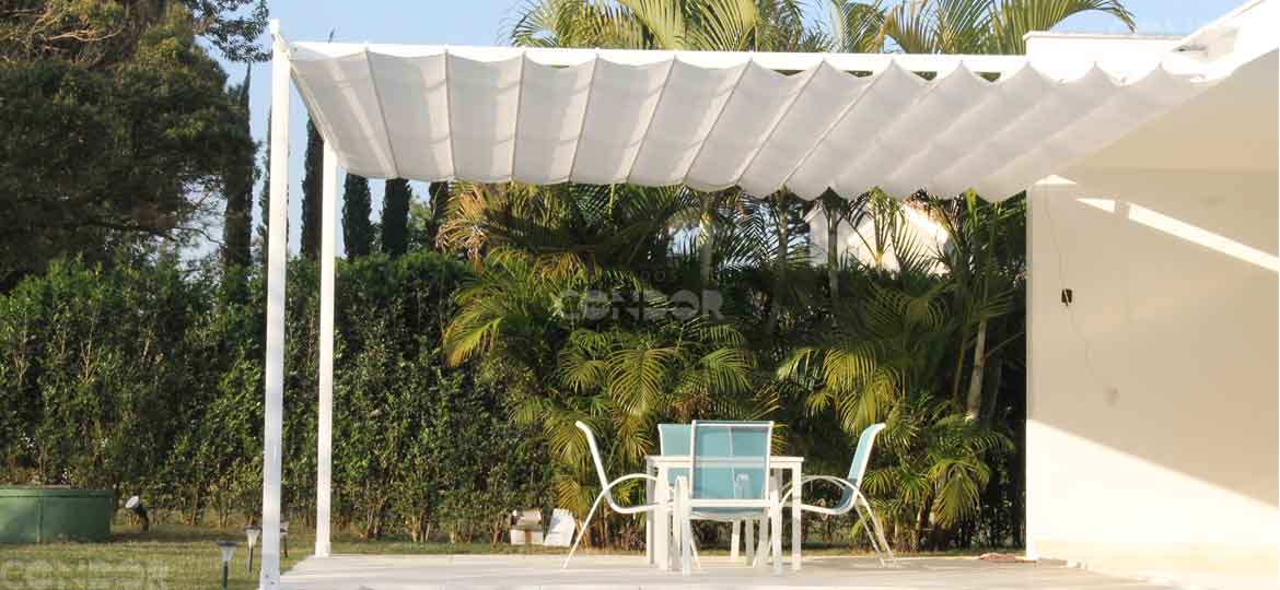 pergola aberta protegendo uma mesa do sol com vista para a floresta.