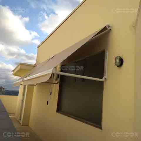toldo retrátil basic aberto protegendo uma grande janela da luz do sol.