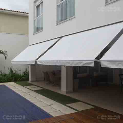 toldos retráteis abertos protegendo uma area gourmet com vista para a piscina.