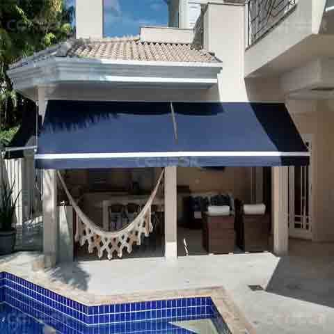 toldos retráteis fazendo sombra para uma area gourmet com rede e vista para uma piscina.