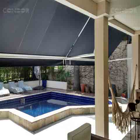toldos retráteis fazendo sombra para uma area gourmet com rede e vista para uma piscina.