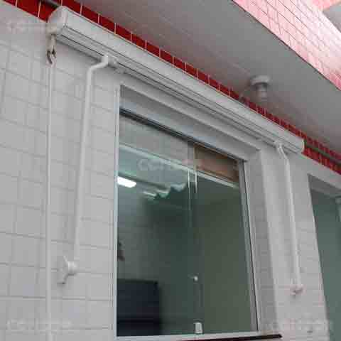 toldo retrátil premium box recolhido em cima de uma porta de vidro.