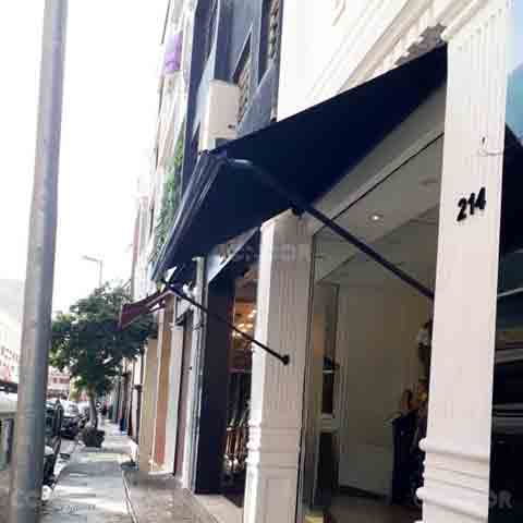 toldo retrátil premium box aberto prtegendo a entrada de uma loja de rua.